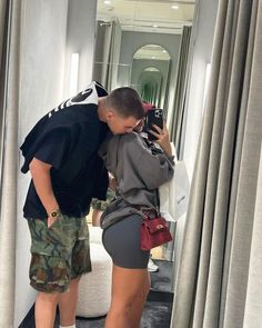 a man and woman taking a selfie in front of a mirror while standing next to each other