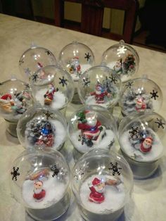 snow globes with santa claus and other christmas decorations in them sitting on a table