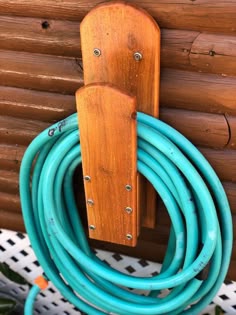 there is a blue hose attached to the wall next to a wooden holder with two rings on it