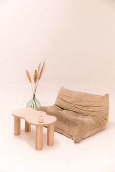 a table with a vase sitting next to it and a couch in front of it