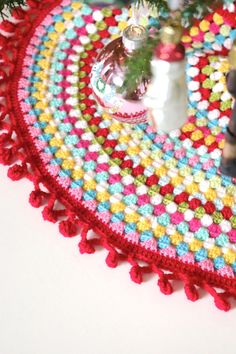 a crocheted christmas tree skirt with ornaments on the top and bottom, sitting on a table