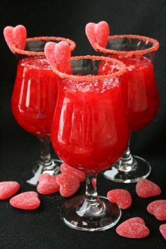 three glasses filled with red liquid surrounded by hearts