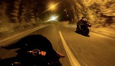 two motorcyclists riding down the road at night