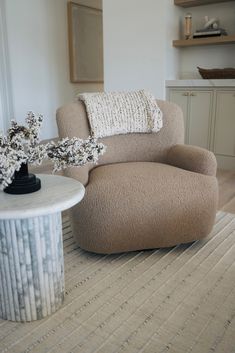 a living room with a chair, coffee table and vase on the rug in front of it