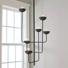 a black chandelier with five lights hanging from it's sides in front of a window