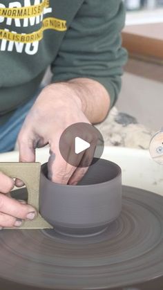 a person is making a vase out of clay on a pottery wheel with one hand