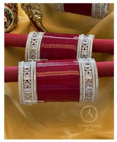 two bracelets are sitting on top of each other in front of a gold cloth