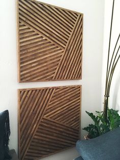 two pieces of wood sitting on top of a white wall next to a potted plant