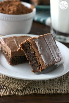 two pieces of chocolate cake on a plate with a glass of milk in the background