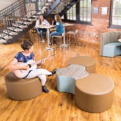 a woman sitting on top of a brown chair next to a table with a guitar