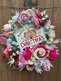 a christmas wreath hanging on the side of a wooden door with candy and candies