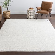 a living room with a white rug and two chairs