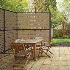 a table and chairs sitting in front of a privacy fence on a brick patio area