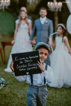 a young boy holding up a sign in front of his bride and grooms on their wedding day