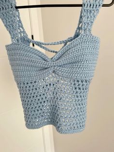 a blue crocheted top hanging from a hook