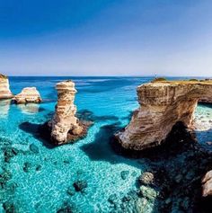 the water is crystal blue and there are two large rocks sticking out of the water