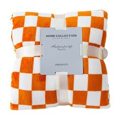 an orange and white checkered pillow with a tag on it's front side