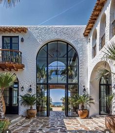 an entrance to a large white building with palm trees and potted plants on either side