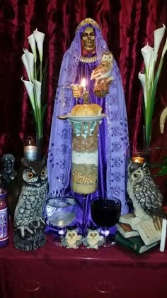 a table topped with an owl figurine next to candles and other decorative items