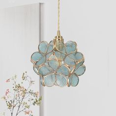 a light fixture with blue flowers hanging from it's side next to a potted plant