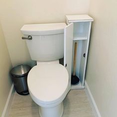 a white toilet sitting in a bathroom next to a trash can