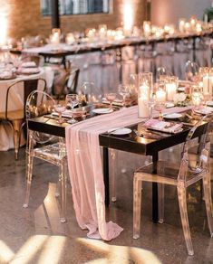 a long table is set with clear chairs, candles and place settings for an elegant dinner