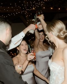 a group of people standing next to each other holding up wine glasses in the air