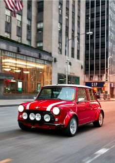 a small red car driving down the street