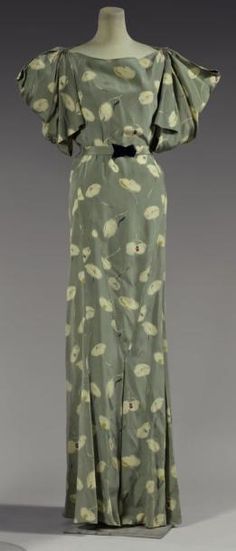 * Robe de Garden Party, 1934, modèle n°4750. Crêpe de soie imprimé, semis de fleurs abstraites ivoire sur fond vert sauge. Manches courtes à découpes donnant un effet drapé, jupe au bas prolongé de plis creux. Ceinture en tissu à fermoir en bakélite noire - Madeleine Vionnet Vionnet Dress, 1930s Fashion Women, 1950s Dresses, 30s Fashion, Garden Party Dress