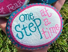 three painted rocks that say one step at a time