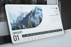 a desk calendar with mountains and trees on it