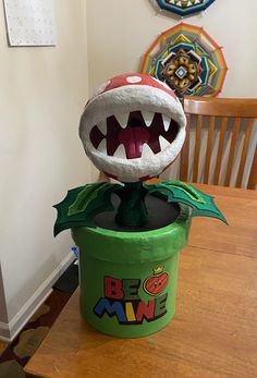 a toy monster sitting on top of a green container with it's mouth open