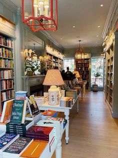 there are many books on the tables in this room and one lamp is hanging from the ceiling