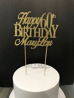 a white cake topped with a gold happy 60th birthday cake topper next to a black background