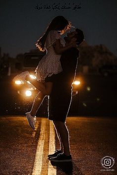 a man and woman dancing on the road at night