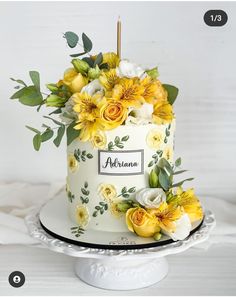 a white cake decorated with yellow flowers and greenery