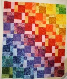 a multicolored quilt hanging on a wall