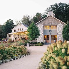 a large white building surrounded by lots of trees and flowers in front of it's entrance