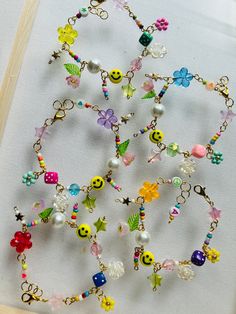 a bunch of bracelets that are sitting on a white surface with flowers and smiley face charms