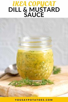 a jar filled with dill and mustard sauce on top of a cutting board