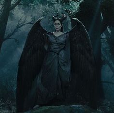 a woman dressed as an angel standing in the woods with her wings spread wide open