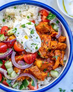 a blue bowl filled with rice, chicken and veggies on top of it