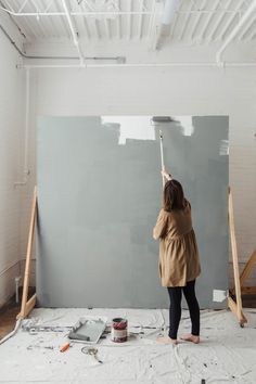 a woman is painting the walls in an empty room