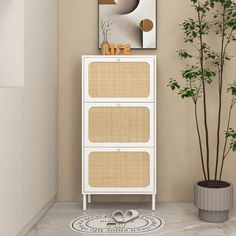 a white cabinet sitting next to a potted plant in a room with beige walls