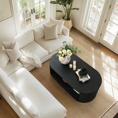 a living room with white couches and pillows on top of the floor next to a coffee table