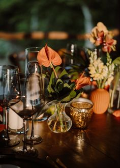 an arrangement of wine glasses and flowers on a table