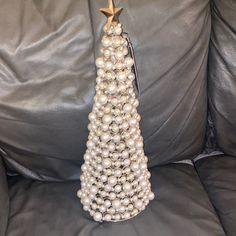 a christmas tree made out of pearls on a gray leather couch with a gold star hanging from the top