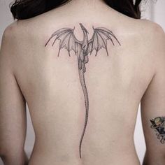 a woman's back with a dragon tattoo on her left side ribcage