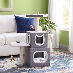 a cat tree in the middle of a living room next to a white couch and green walls