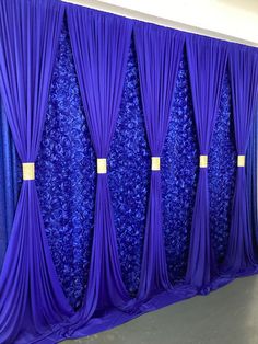 blue drapes are hanging on the wall in front of a purple backdrop with gold tags